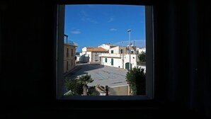 A view through a window of a street with buildings, a clear sky, and a few trees. - Appartamento Calipso (Santa Croce Camerina)