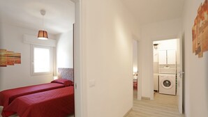 Habitación de hotel pequeña con dos camas individuales, un ventanal, una lámpara en el techo y vistas al lavadero de al lado.