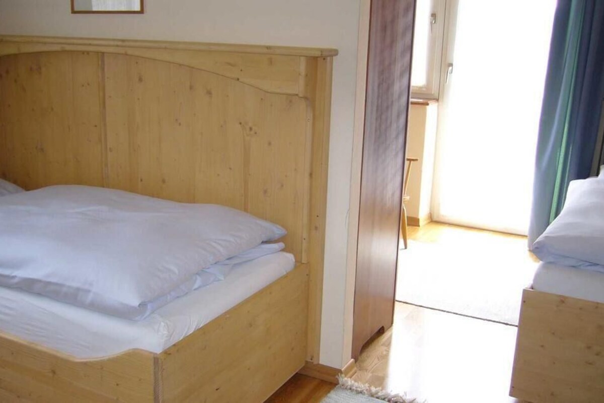 Una cama de madera individual con ropa de cama blanca en una habitación con cabecera de madera.
