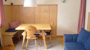 Ein gemütlicher Raum mit einem Holztisch und -stühlen, einem blauen Sofa und einer Bank mit Kissen.
