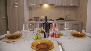 Una mesa de comedor dispuesta con platos, vasos y una botella de vino en una cocina moderna.
