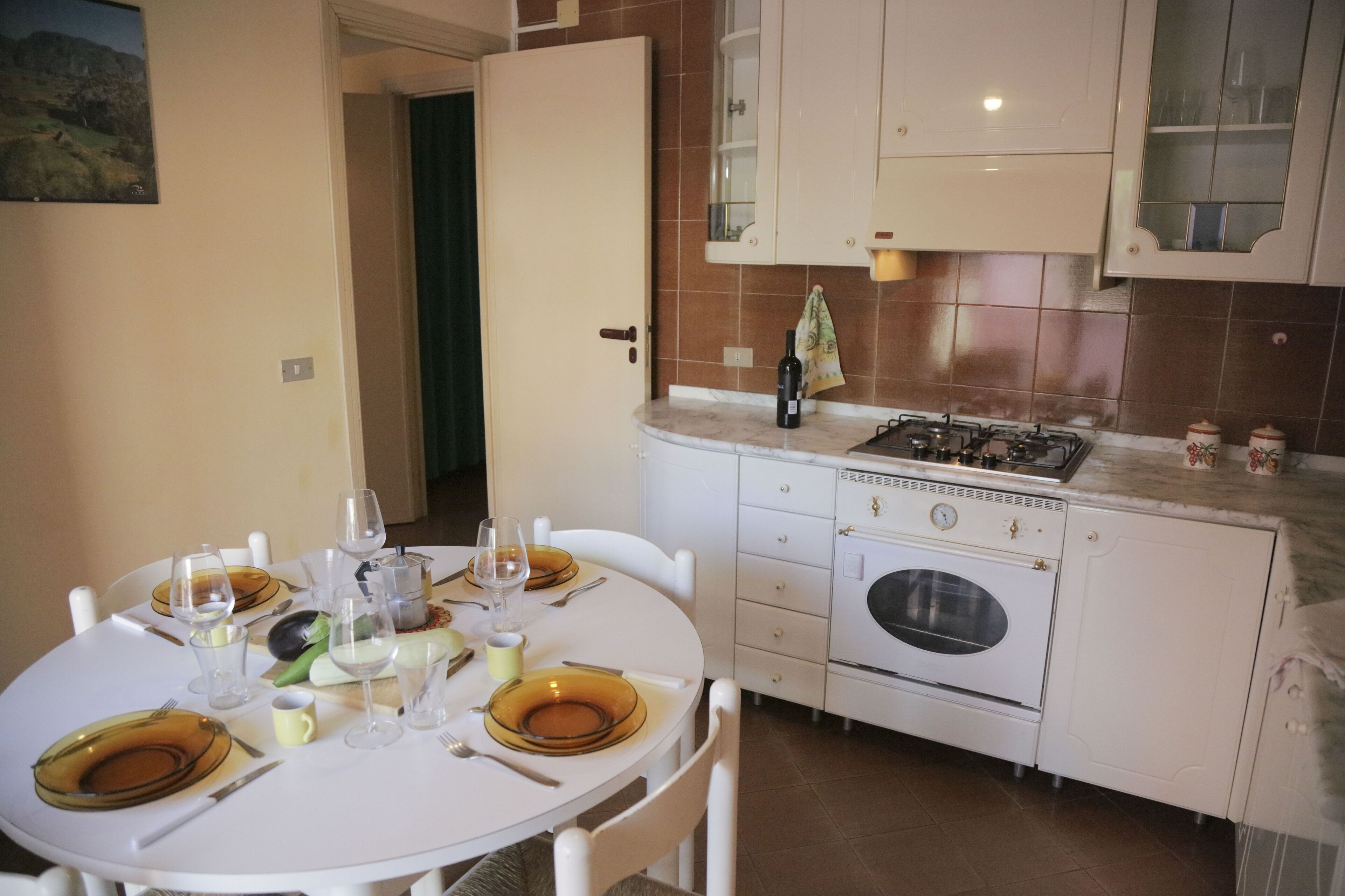 Une cuisine équipée d’une table à manger pour quatre personnes, d’une cuisinière, d’un four et de placards.
