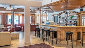 Un espace bar avec des tabourets de bar en bois, un comptoir et une variété de bouteilles et de verres.