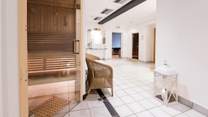 A modern interior with a wooden sauna area, a wicker chair, and a white lantern. - Hotel Rothirsch by Skinetworks (Sankt Johann im Pongau)