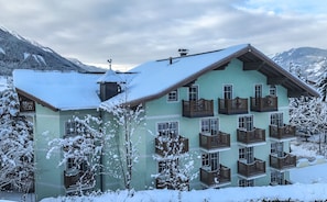 A multi-story building with balconies, surrounded by snow-covered trees and mountains. - Hotel Rothirsch by Skinetworks (Sankt Johann im Pongau)