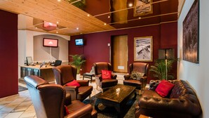 A modern lounge area with leather sofas, a coffee table, and a TV mounted on the wall. - Hotel Rothirsch by Skinetworks (Sankt Johann im Pongau)