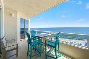 Enjoy ocean views from this balcony with a table and chairs.