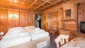A wooden room with a bed, a chair, a desk, and a television. - Heart Hotel Talhoff Nigg (Sankt Anton am Arlberg)