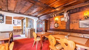 A wooden interior with a red carpet, wooden tables and chairs, a fireplace, and antlers on the wall. - Heart Hotel Talhoff Nigg (Sankt Anton am Arlberg)