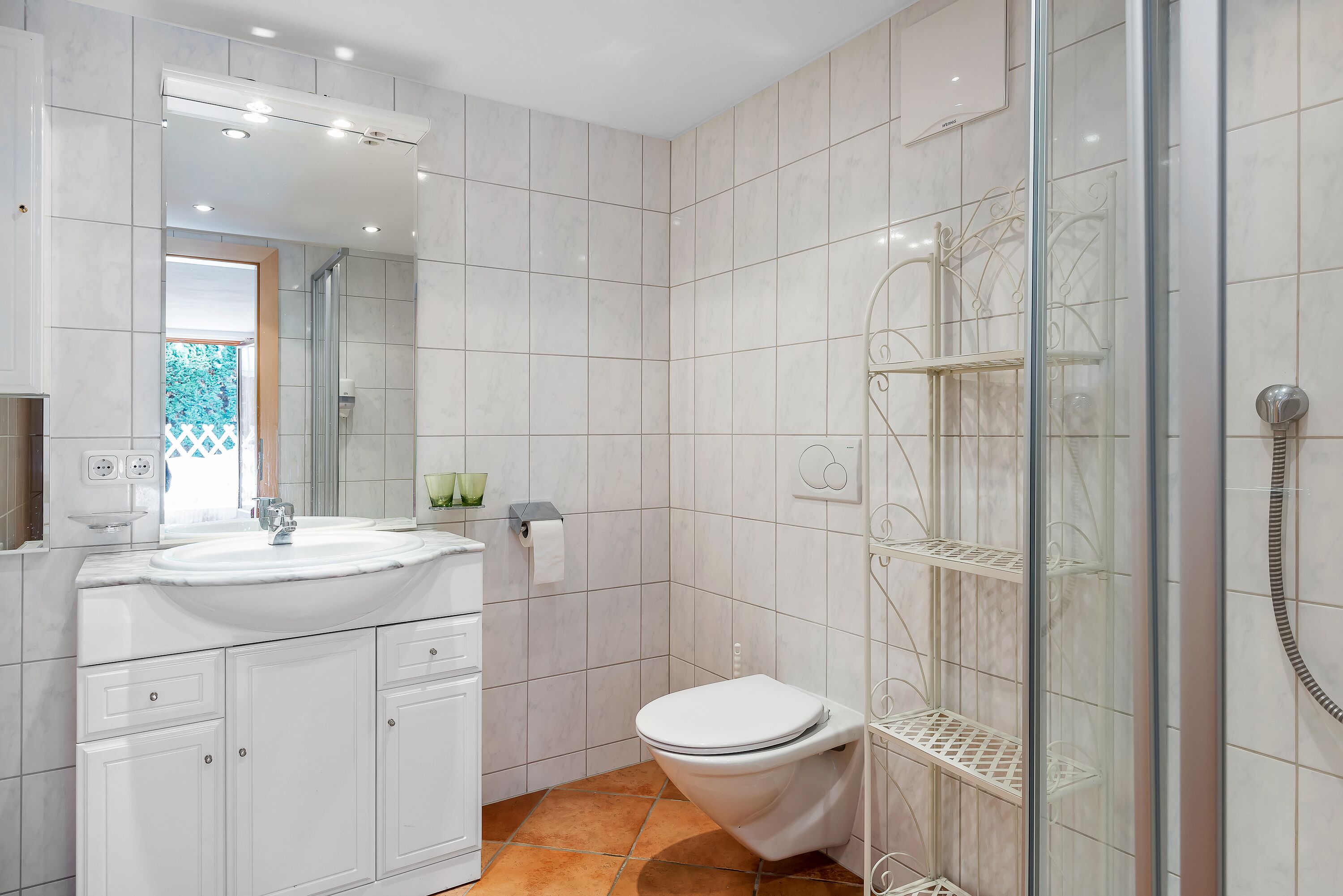A modern bathroom with a white sink, toilet, and glass shower enclosure.