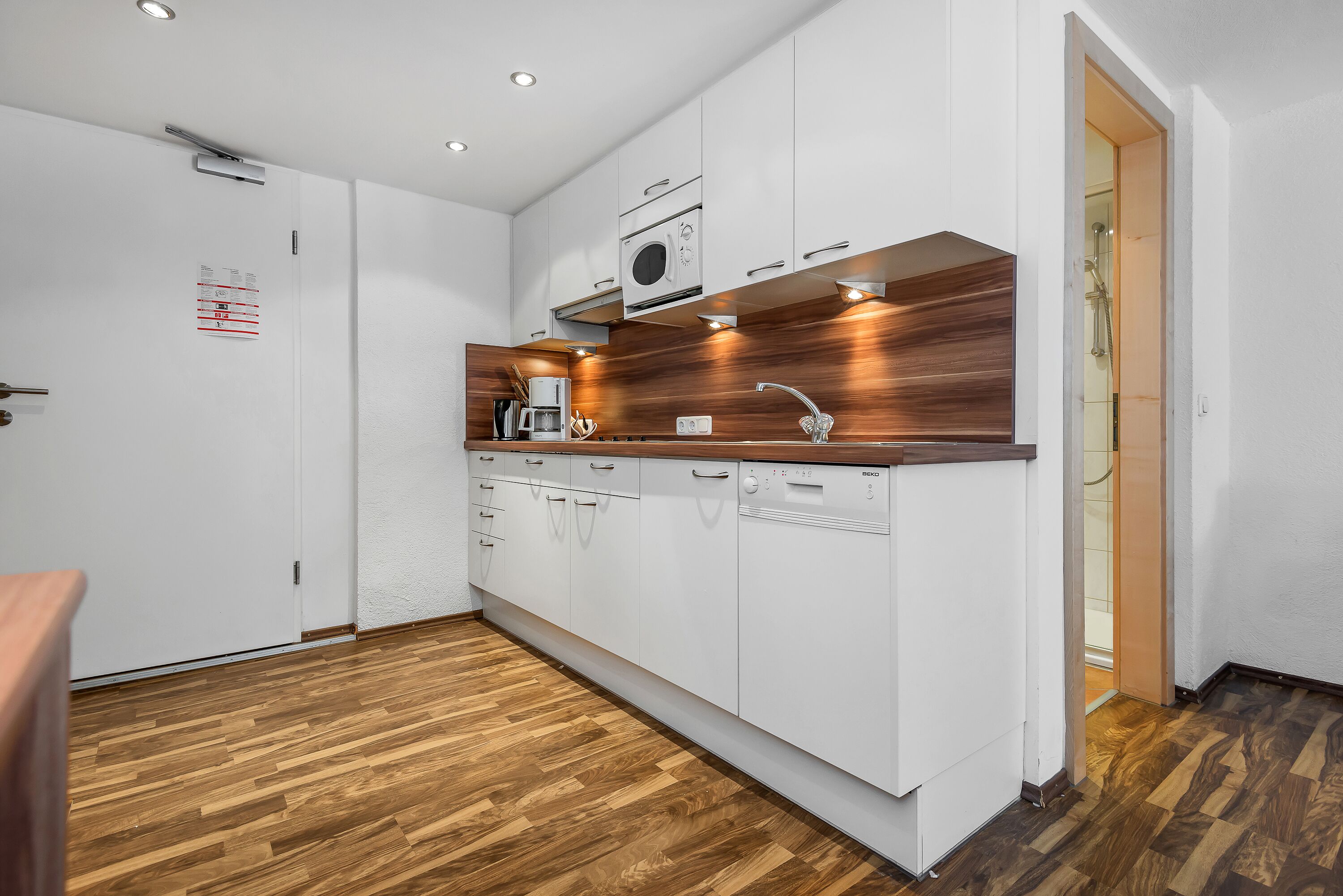 A modern kitchen with white cabinets, a wooden countertop, and a built-in oven.