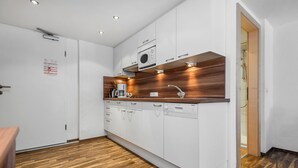 Une cuisine moderne avec des armoires blanches, un plan de travail en bois et un four encastré.