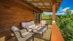Eine Holzterrasse mit Korbmöbeln und Blick ins Waldgebiet.