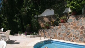 A swimming pool with a stone wall and potted plants. - 2 -Spectacular apartment with sea view, large terrace, 4 min. walk to the beach (Roses)