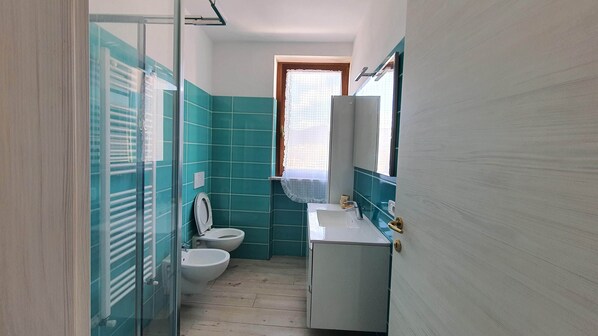 A bathroom with a toilet, bidet, and a sink with a mirror.