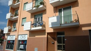 A multi-story building with balconies, a storefront with 'OVS' signage, and a stop sign in the foreground. - Appartamenti Le Maree (Portoferraio)