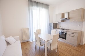 Uma cozinha moderna com mesa e cadeiras, forno embutido e armários em tons claros.