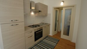 A modern kitchen with light wood cabinetry, a gas stove, a built-in oven, and a stainless steel sink. - Appartamenti Le Maree (Portoferraio)