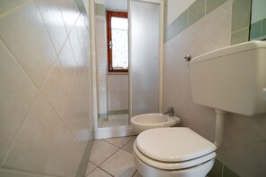 Et badeværelse med toilet, bidet og bruseområde.