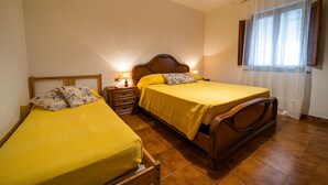 A bedroom with two beds, wooden headboards, and a window with curtains. - Bilocale La Terrazza sul Mare (Campo nell'Elba)