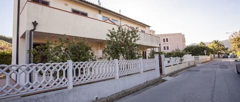 A residential street with houses, a white fence, and a clear sky.