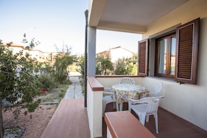 Un patio con tavolo e sedie, un piccolo giardino e vista sulle case vicine.