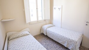 Une petite pièce propre, avec deux lits simples, une fenêtre et une porte.