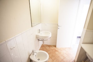 Ein kleines Badezimmer mit zwei Waschbecken, einem Spiegel und einer Tür zu einem weiteren Raum.