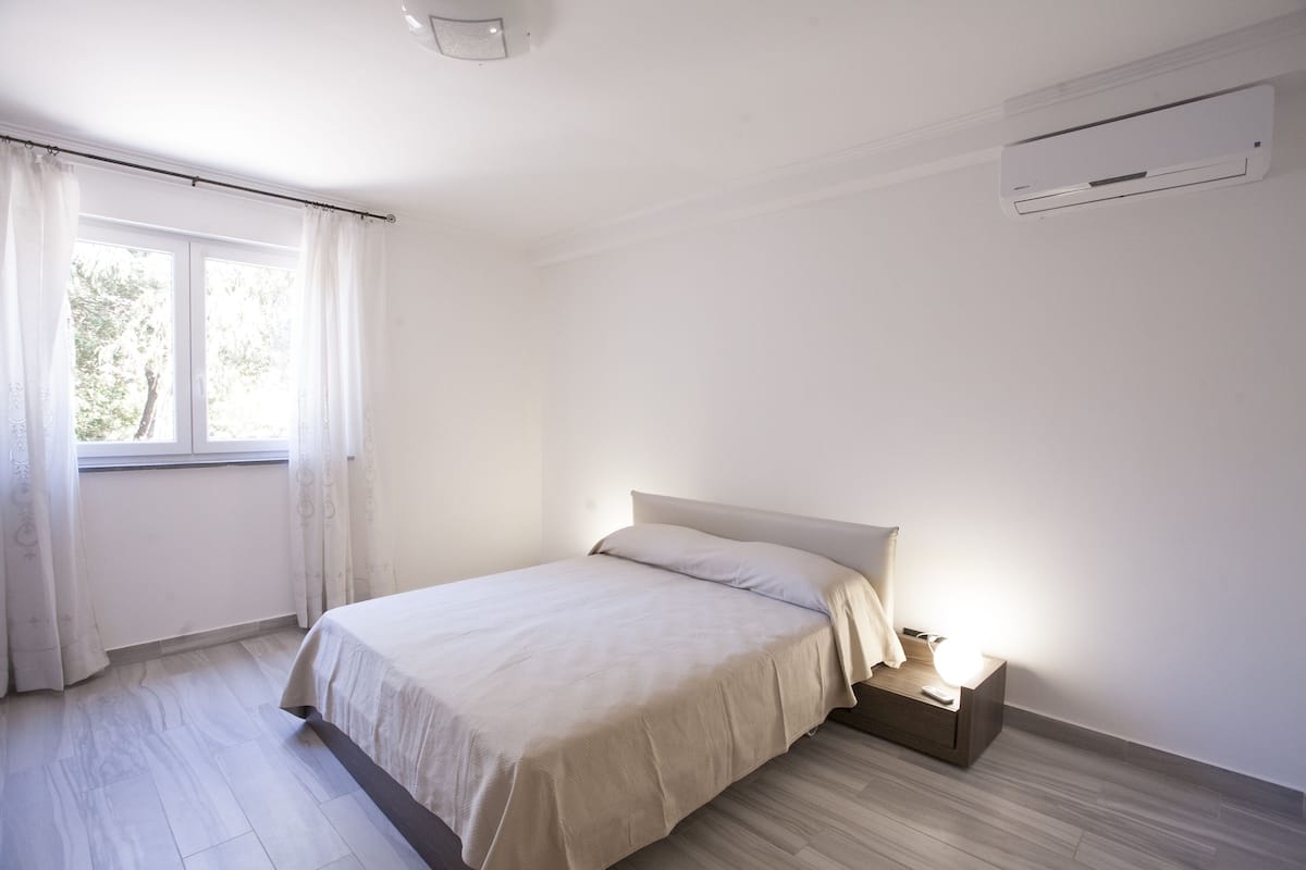 Un dormitorio con cama, mesita de noche y unidad de aire acondicionado.