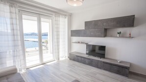 Ett modernt vardagsrum med ett stort fönster, en platt-TV och en minimalistisk design.