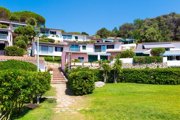 A hillside residential area with terraced houses, a stone pathway, and lush greenery.