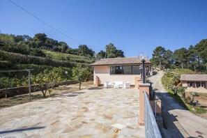 A modern house with a tiled patio, outdoor seating, and a view of the surrounding landscape. - Residenza Il Gabbiano (Capoliveri)