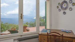 A room with a view of the sea, a wooden table, a chair, and a wall with decorative plates. - Villa Il Leccio sul Mare (Portoferraio)