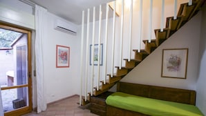 A staircase with wooden steps and white railings, a wooden bench with a green cushion, and a door leading outside. - Appartamenti Home 75 (Portoferraio)