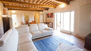 A spacious living room with a large white sectional sofa, a blue rug, and a wooden ceiling. - Villetta Paradiso (Portoferraio)