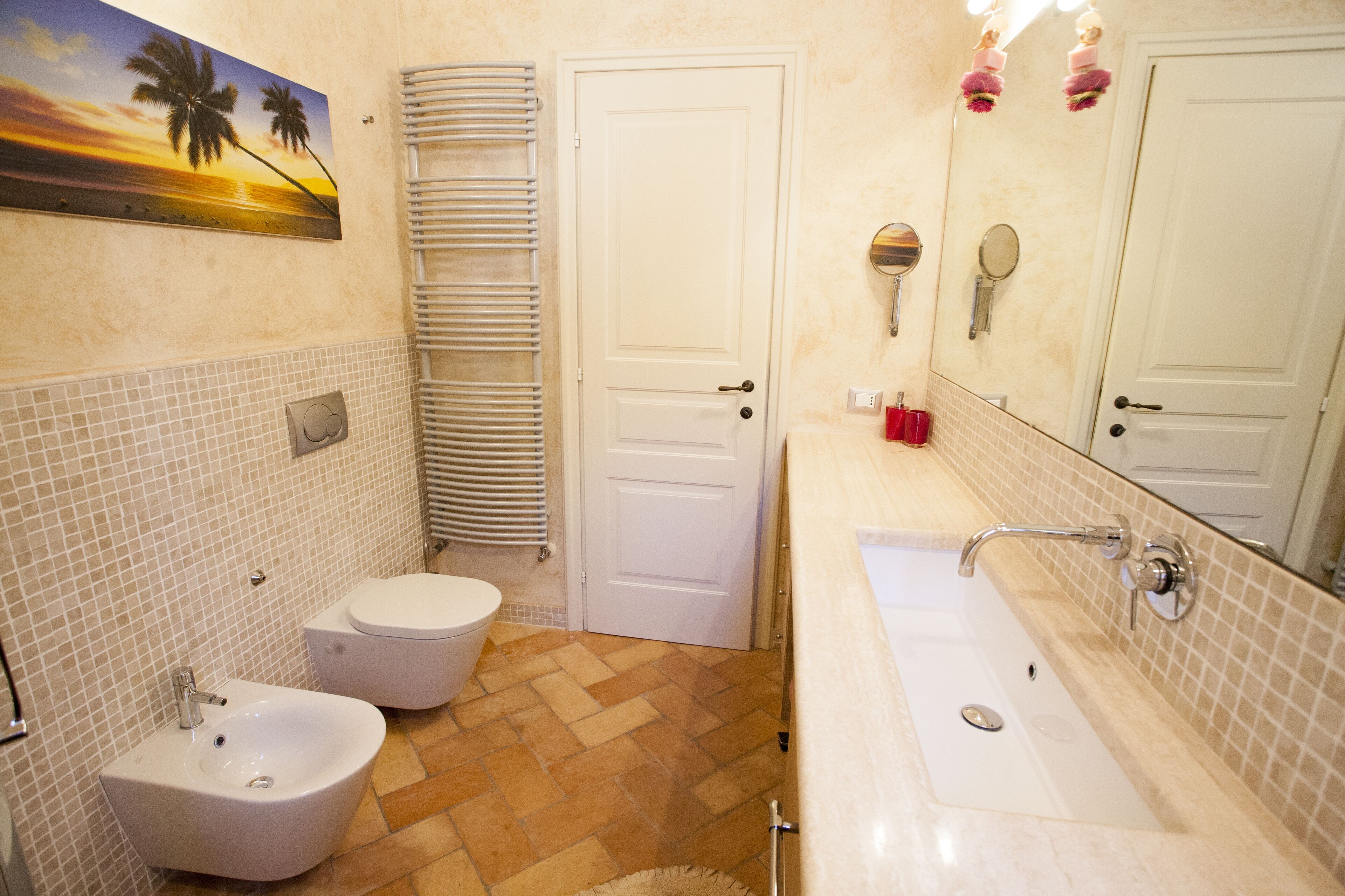A bathroom with a bidet, toilet, sink, and a large mirror.