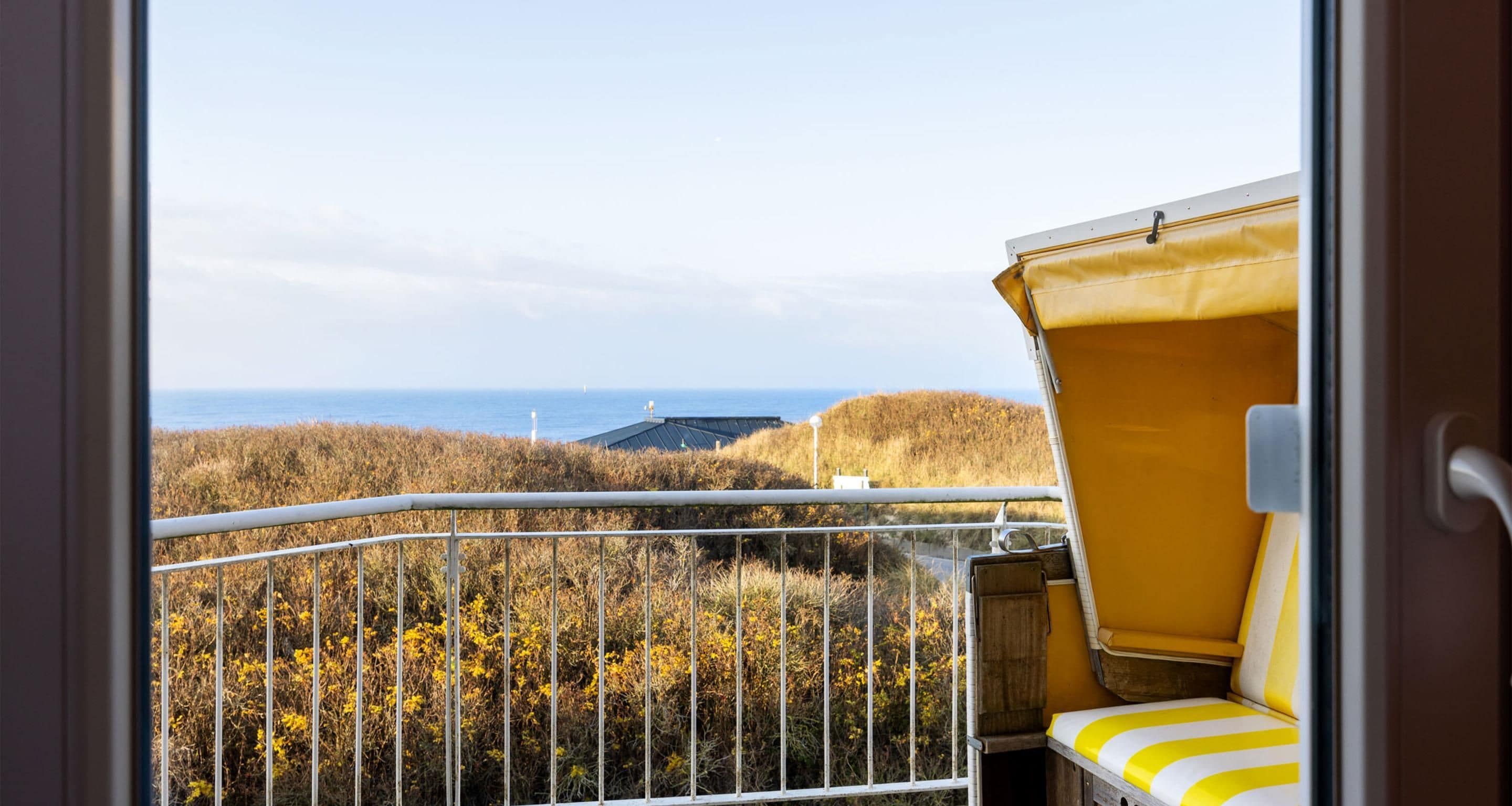 Ein Balkon mit Blick auf das Meer und ein Gebäude in der Ferne.