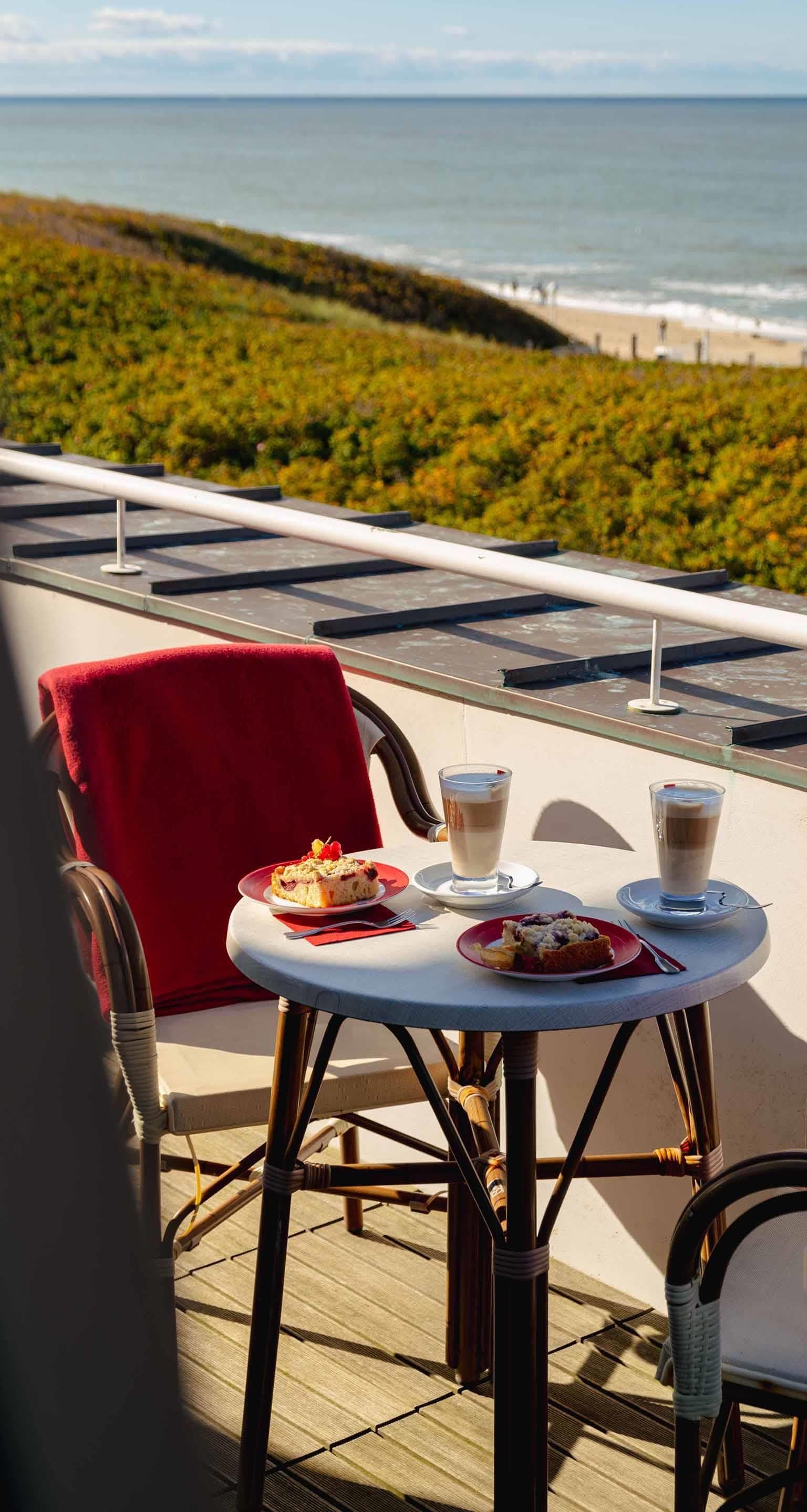 Une terrasse avec une table dressée pour deux personnes, donnant sur une plage.