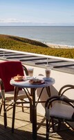 A seaside terrace with tables, chairs, and a view of the ocean.