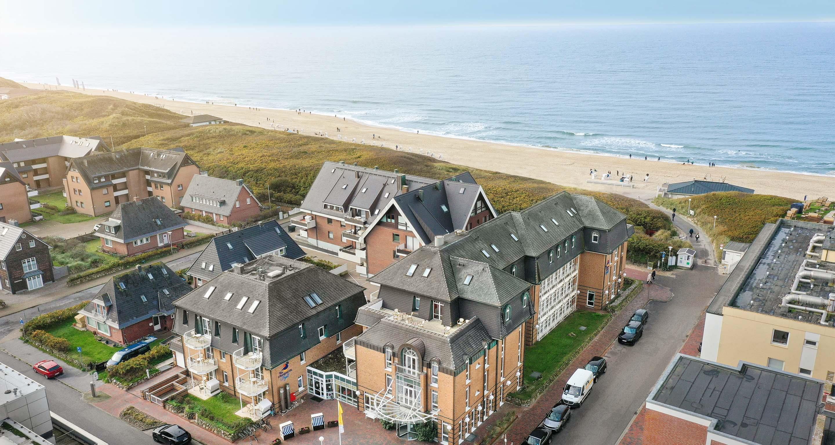A coastal residential area with houses, a beach, and a clear view of the sea.