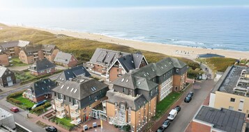 A coastal residential area with houses, a beach, and a clear view of the sea.