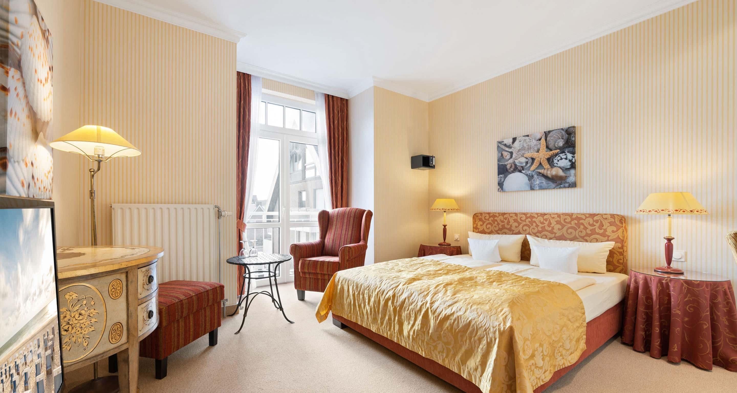 Ein Hotelzimmer mit Bett, Sessel, Schreibtisch, Lampe und einem Gemälde an der Wand.