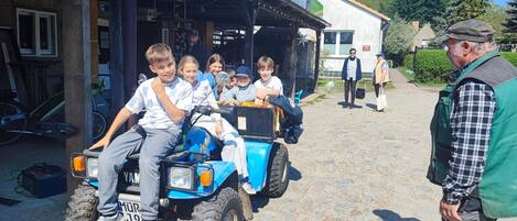 Un grupo de niños en un vehículo todo terreno azul frente a un edificio con un letrero que dice 'SOMER'.