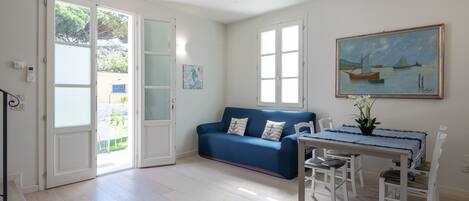 A room with a blue sofa, a dining table with chairs, and a painting on the wall.