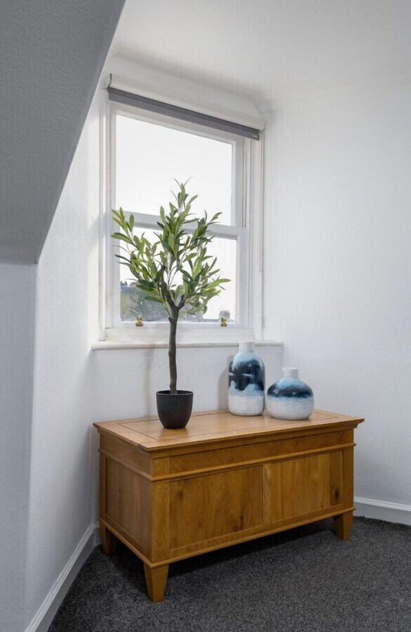 Une pièce d’angle avec un banc en bois, une plante en pot et deux vases.