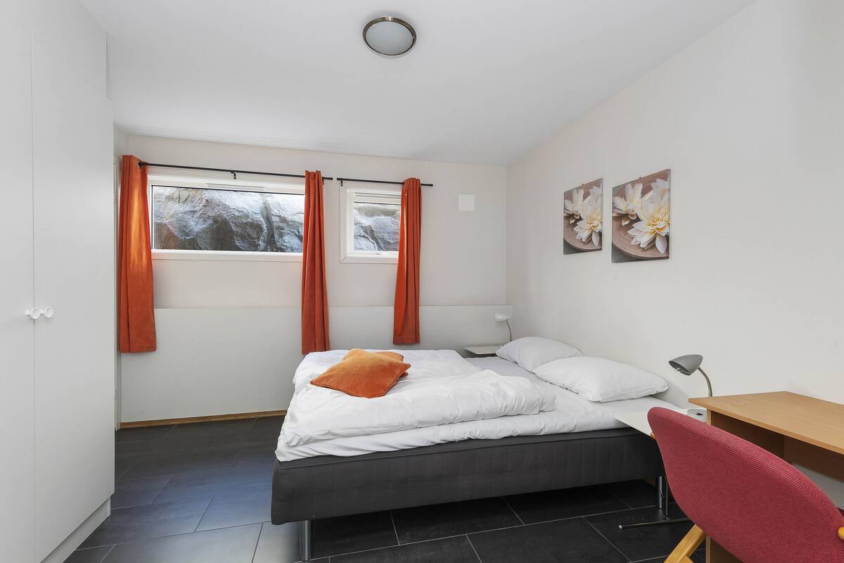 A modern bedroom with a bed, a desk, and a chair.