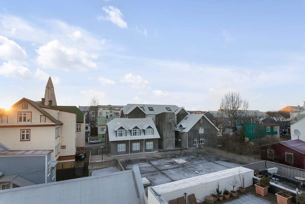 Un barrio residencial con casas, la aguja de una iglesia y un cielo despejado.