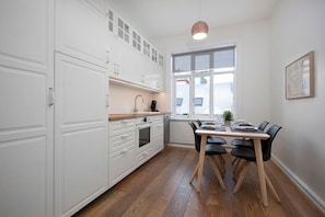 Una cocina moderna con armarios blancos, una mesa de comedor con sillas y un ventanal grande.