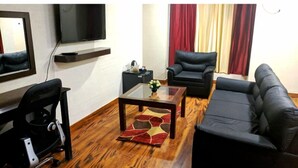 Una sala de estar moderna con un sofá, dos sillones, una mesa de centro y un televisor montado en la pared.