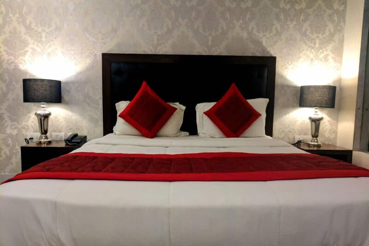 Una habitación de hotel con una cama grande, dos mesitas de noche y dos lámparas.